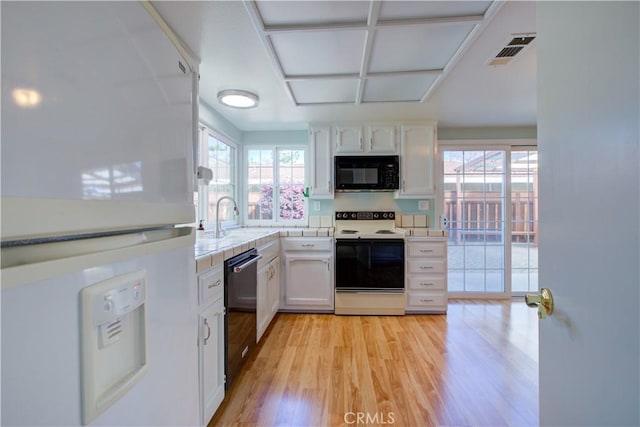 kitchen with visible vents, black appliances, light countertops, light wood-type flooring, and white cabinetry