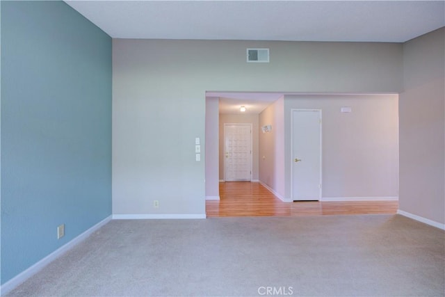 carpeted spare room with visible vents and baseboards