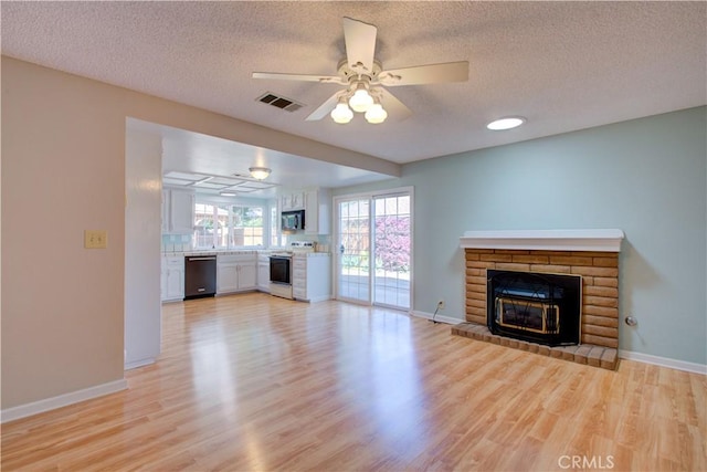 unfurnished living room featuring visible vents, baseboards, a brick fireplace, and light wood-style flooring