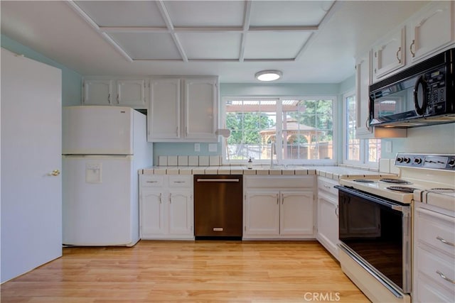 kitchen with white appliances, tile counters, white cabinets, and a sink