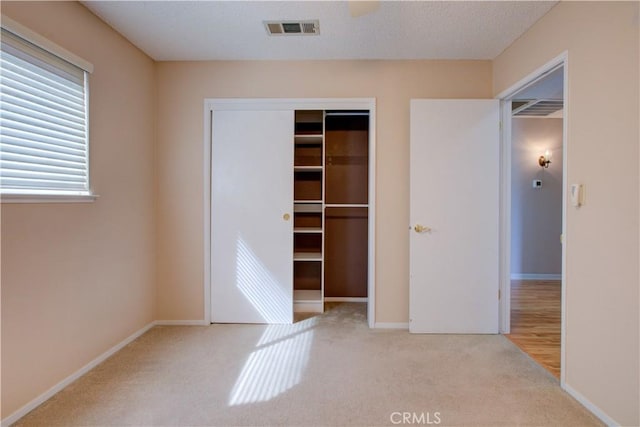 unfurnished bedroom with baseboards, visible vents, carpet floors, and a closet