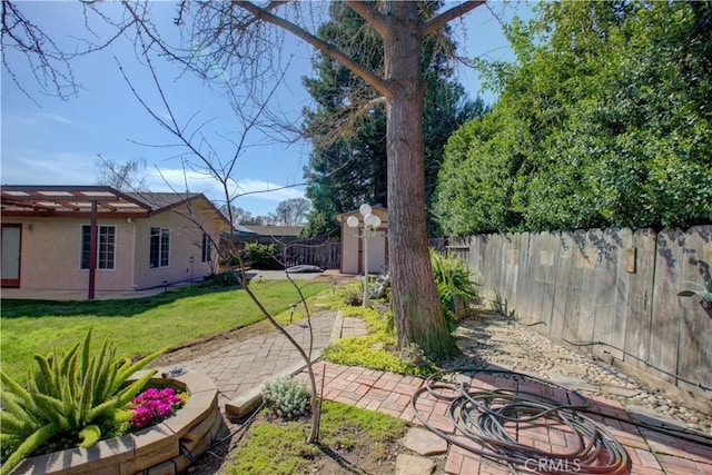 view of yard featuring an outdoor structure, a fenced backyard, and a patio