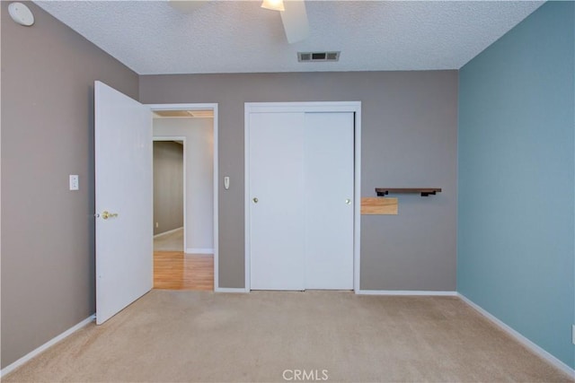 unfurnished bedroom featuring a closet, visible vents, carpet flooring, and a textured ceiling