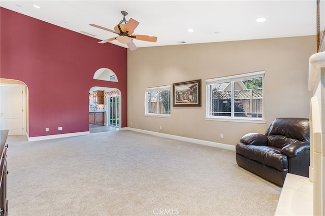 carpeted living room with high vaulted ceiling, recessed lighting, arched walkways, baseboards, and ceiling fan