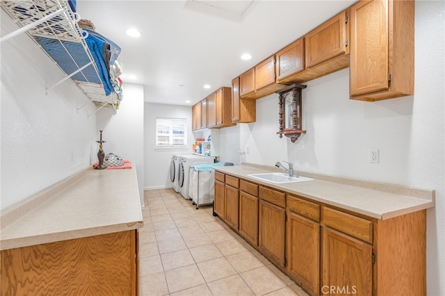 kitchen with light tile patterned floors, brown cabinetry, a sink, light countertops, and washer and clothes dryer