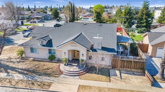 view of front of house with stucco siding, fence private yard, a residential view, and a chimney