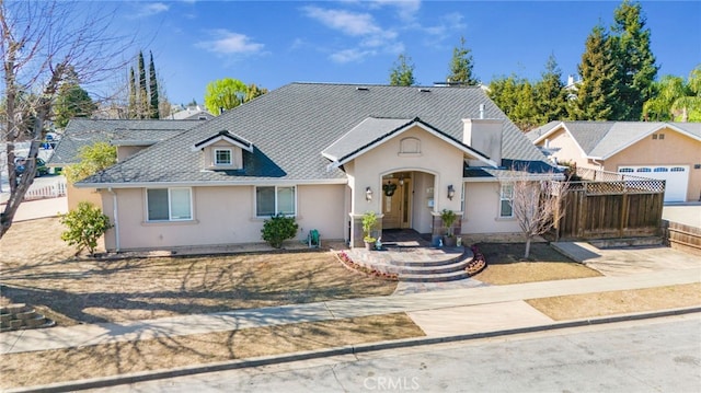 view of front of home with a shingled roof, fence, and stucco siding