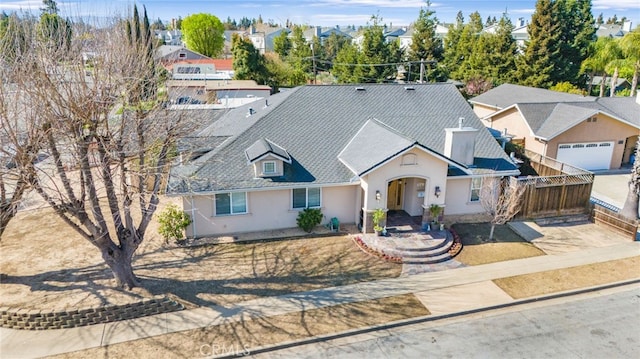 view of front of home with a residential view, stucco siding, roof with shingles, and fence