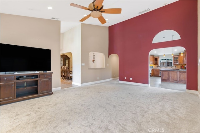 unfurnished living room with visible vents, arched walkways, and light carpet