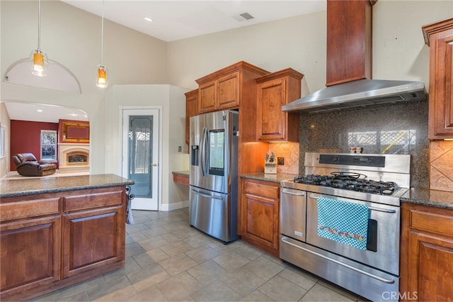 kitchen with visible vents, brown cabinets, tasteful backsplash, stainless steel appliances, and wall chimney range hood