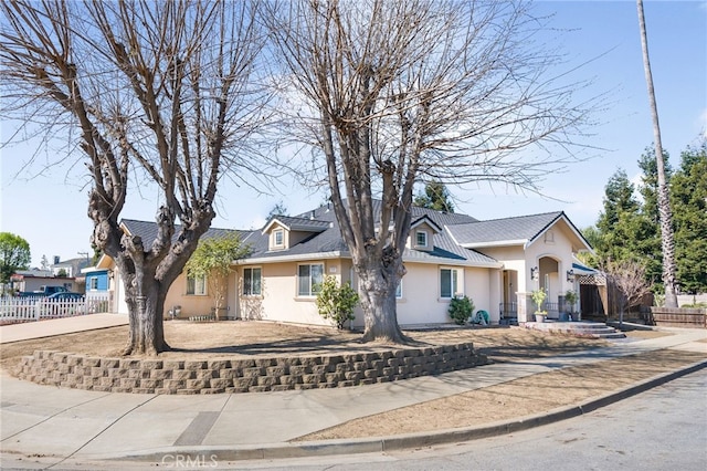 view of front of home featuring stucco siding, concrete driveway, and fence