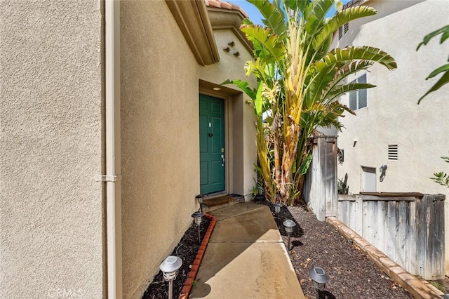 property entrance with fence and stucco siding