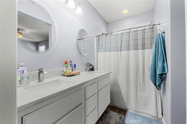 full bathroom with a sink, wood finished floors, ceiling fan, and double vanity