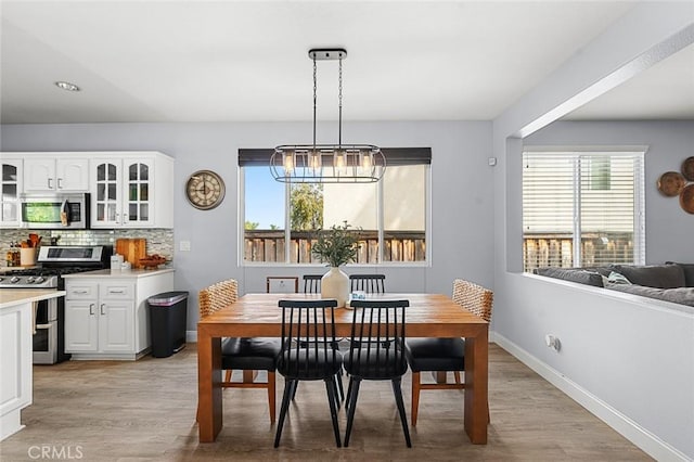 dining room featuring plenty of natural light, light wood-style flooring, and an inviting chandelier