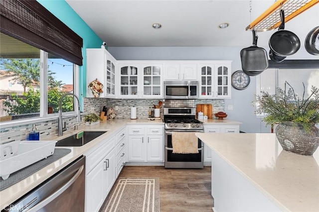 kitchen featuring a sink, wood finished floors, white cabinetry, and stainless steel appliances