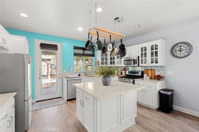 kitchen featuring a sink, glass insert cabinets, light wood-type flooring, and appliances with stainless steel finishes