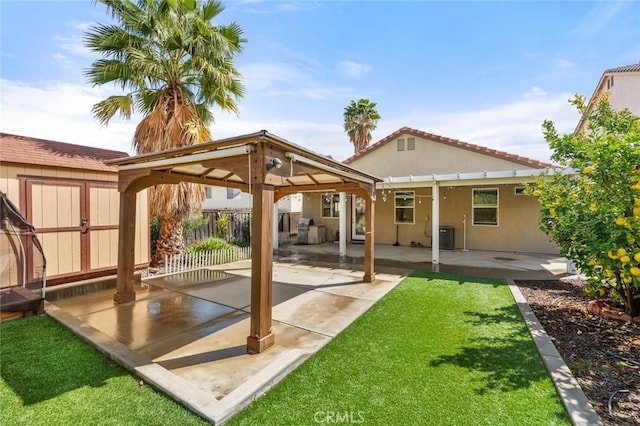 back of property with stucco siding, a lawn, fence, a gazebo, and a patio area