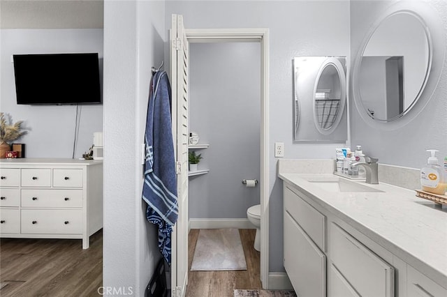 full bathroom featuring baseboards, toilet, wood finished floors, and vanity