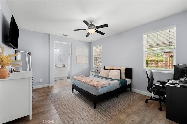 bedroom featuring visible vents, a ceiling fan, wood finished floors, connected bathroom, and baseboards