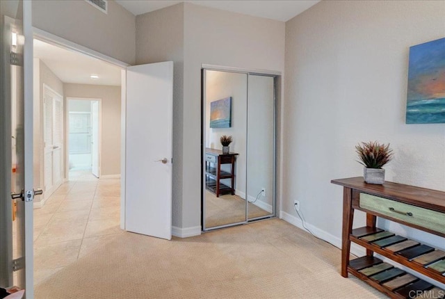 interior space with visible vents, baseboards, light colored carpet, light tile patterned floors, and a closet