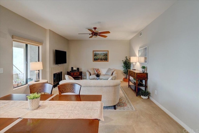 living room featuring visible vents, baseboards, ceiling fan, light carpet, and a glass covered fireplace