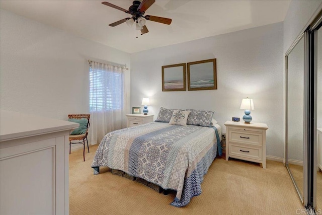 bedroom with a closet, baseboards, light colored carpet, and ceiling fan