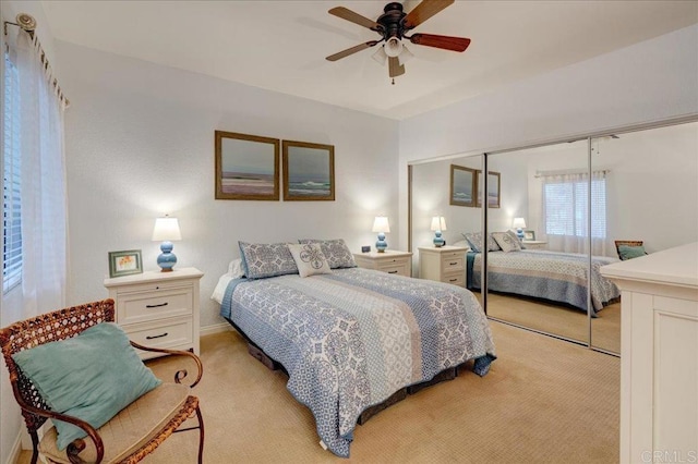 bedroom featuring a closet, light colored carpet, and ceiling fan