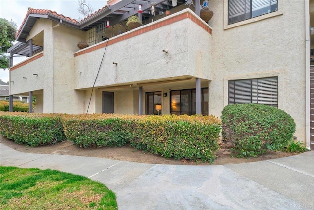 exterior space with a tile roof and stucco siding