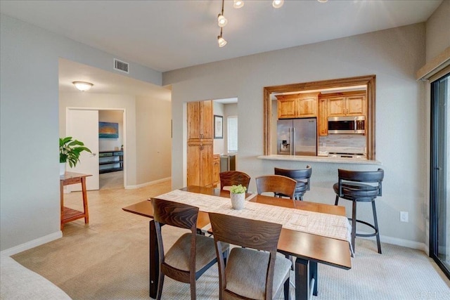 dining area featuring light carpet, visible vents, and baseboards