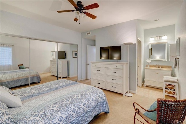 bedroom featuring visible vents, connected bathroom, a closet, a ceiling fan, and a sink