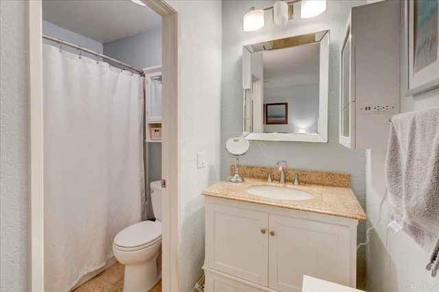 full bathroom featuring tile patterned floors, toilet, vanity, and a textured wall