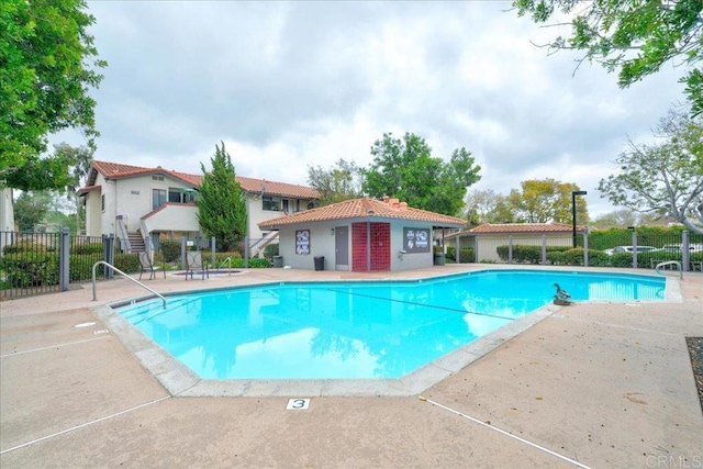 community pool with a patio and fence