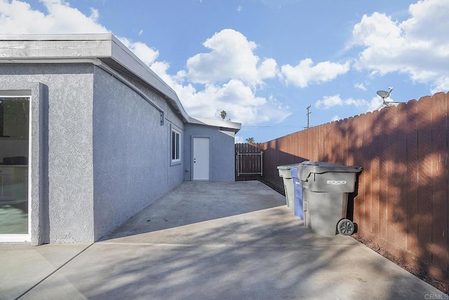 view of property exterior featuring a patio, fence, and stucco siding