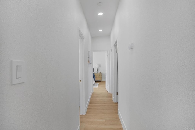 hall featuring recessed lighting, baseboards, and light wood-style flooring