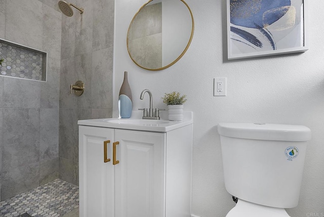 full bathroom featuring toilet, vanity, and a tile shower