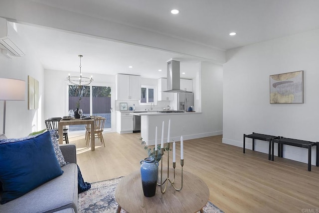 living area with an inviting chandelier, recessed lighting, light wood finished floors, and a wall mounted AC