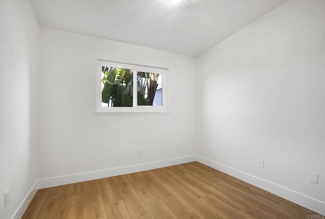 spare room with baseboards and light wood-type flooring