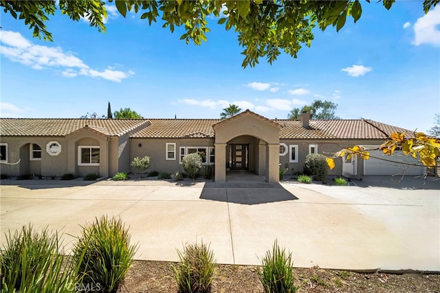 mediterranean / spanish home with a tiled roof, a chimney, and stucco siding