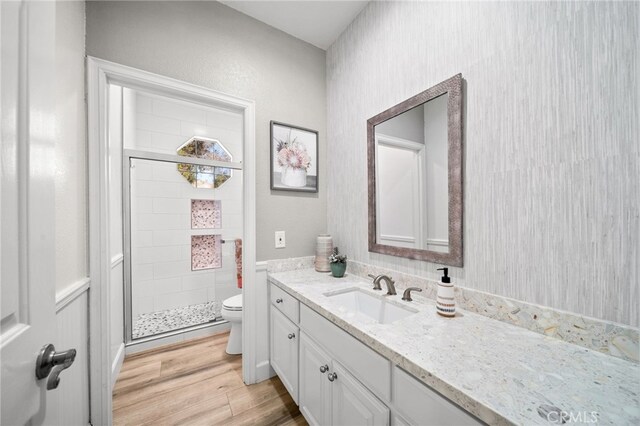 bathroom featuring a stall shower, toilet, wood finished floors, and vanity