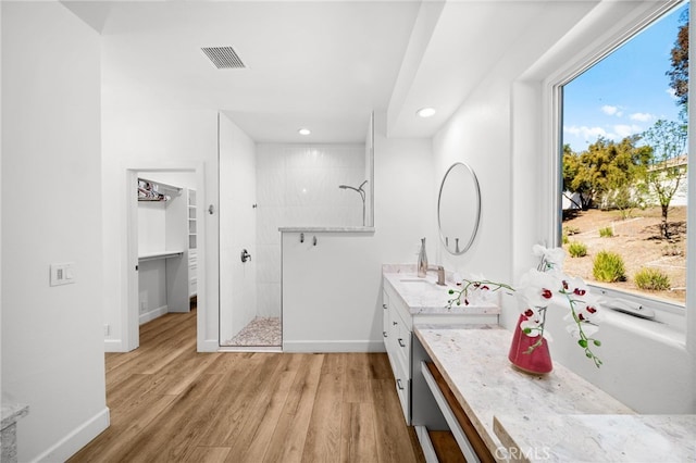 bathroom with visible vents, wood finished floors, baseboards, walk in shower, and vanity