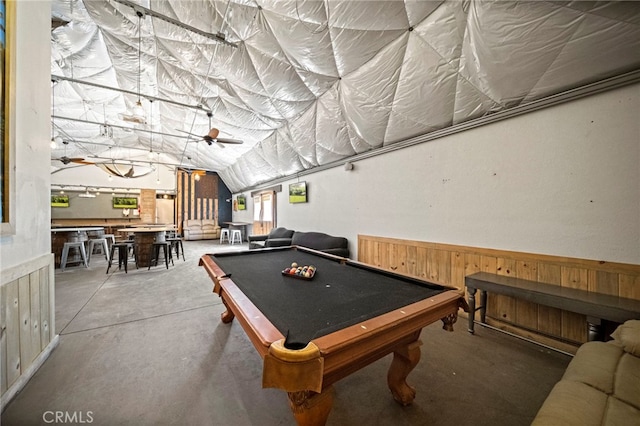 recreation room with wooden walls, pool table, concrete floors, ceiling fan, and lofted ceiling