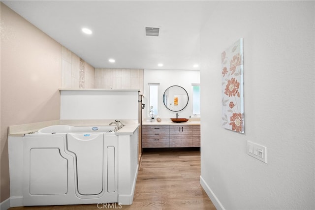 laundry room featuring visible vents, a sink, recessed lighting, light wood-style floors, and baseboards