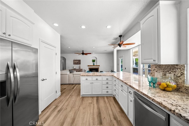 kitchen with light wood-type flooring, a ceiling fan, appliances with stainless steel finishes, a peninsula, and white cabinets