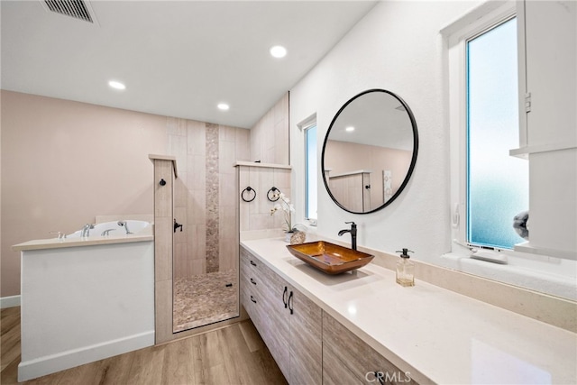 bathroom with vanity, wood finished floors, visible vents, tiled shower, and recessed lighting