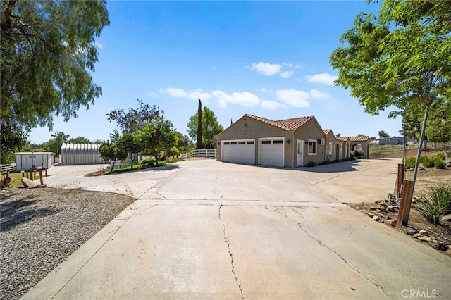 view of home's exterior featuring stucco siding, driveway, fence, a garage, and a tiled roof