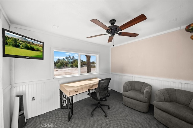 home office featuring ceiling fan, crown molding, dark carpet, and wainscoting