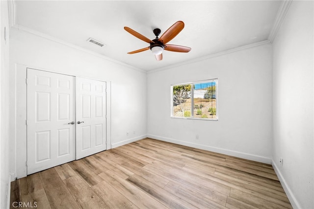 unfurnished bedroom with visible vents, light wood-type flooring, baseboards, and ornamental molding