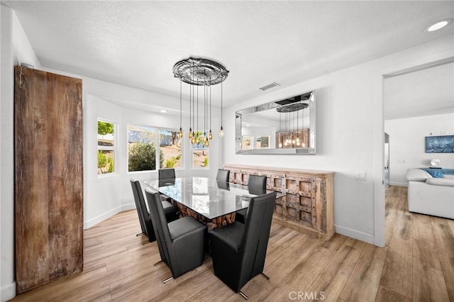 dining area featuring visible vents, baseboards, a textured ceiling, and light wood finished floors