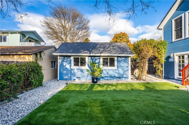 rear view of property with a shingled roof, fence, a lawn, and crawl space