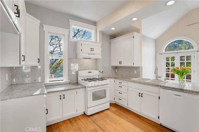 kitchen featuring white appliances, lofted ceiling, a sink, white cabinetry, and light wood-type flooring